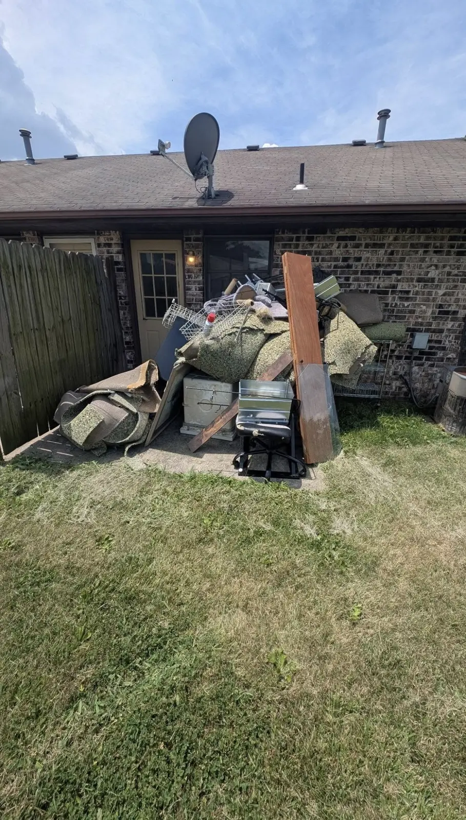 Backyard patio piled with furniture and junk before removal