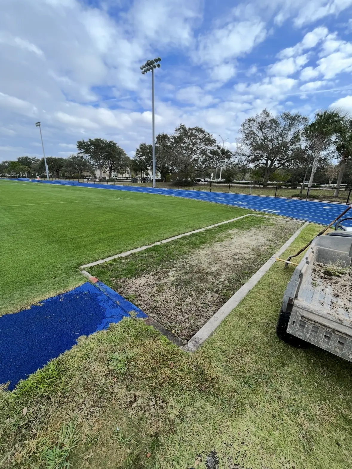 Athletic field work area with patchy grass before clearing